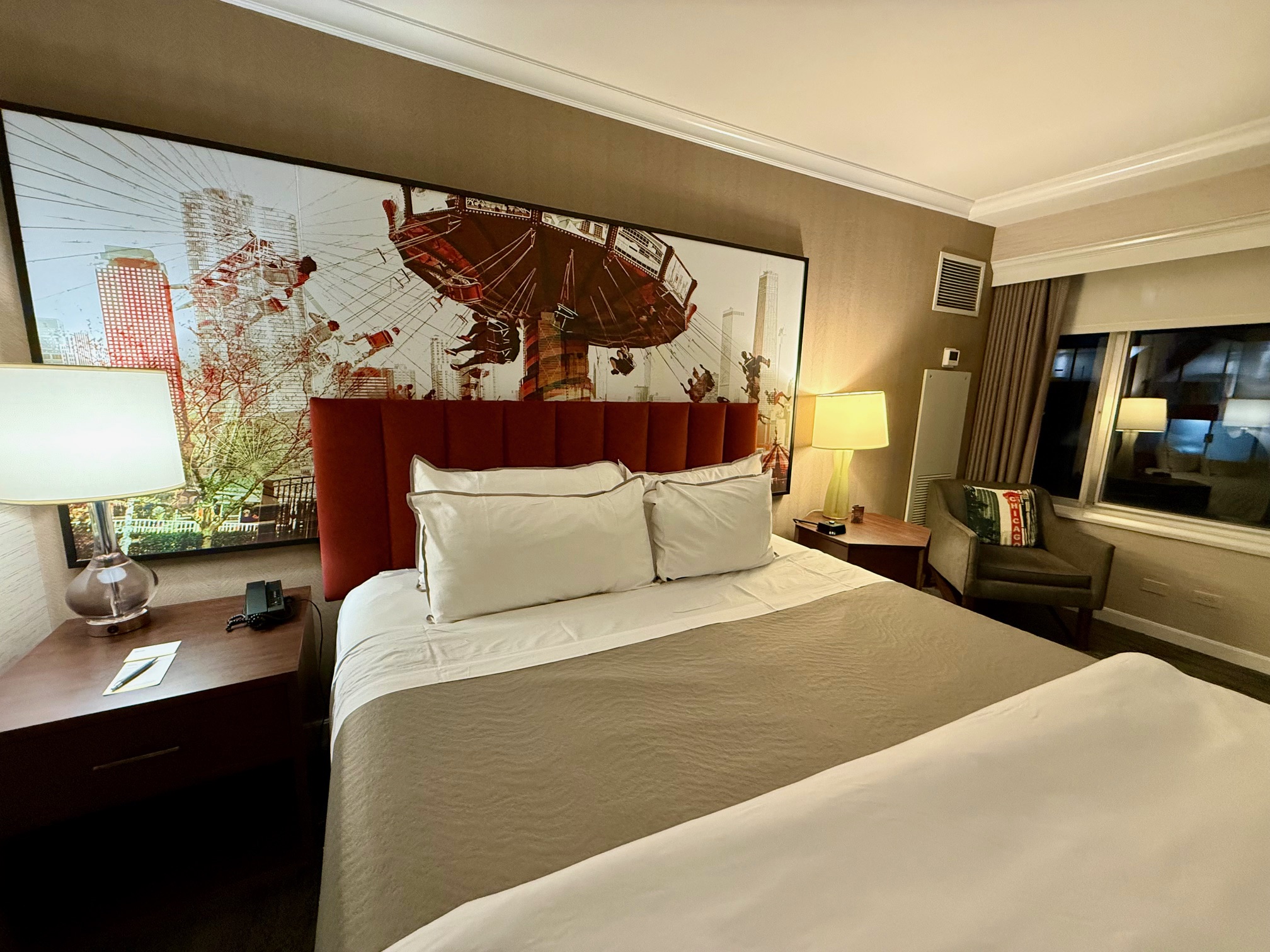 a bed with a red headboard and a lamp in a hotel room