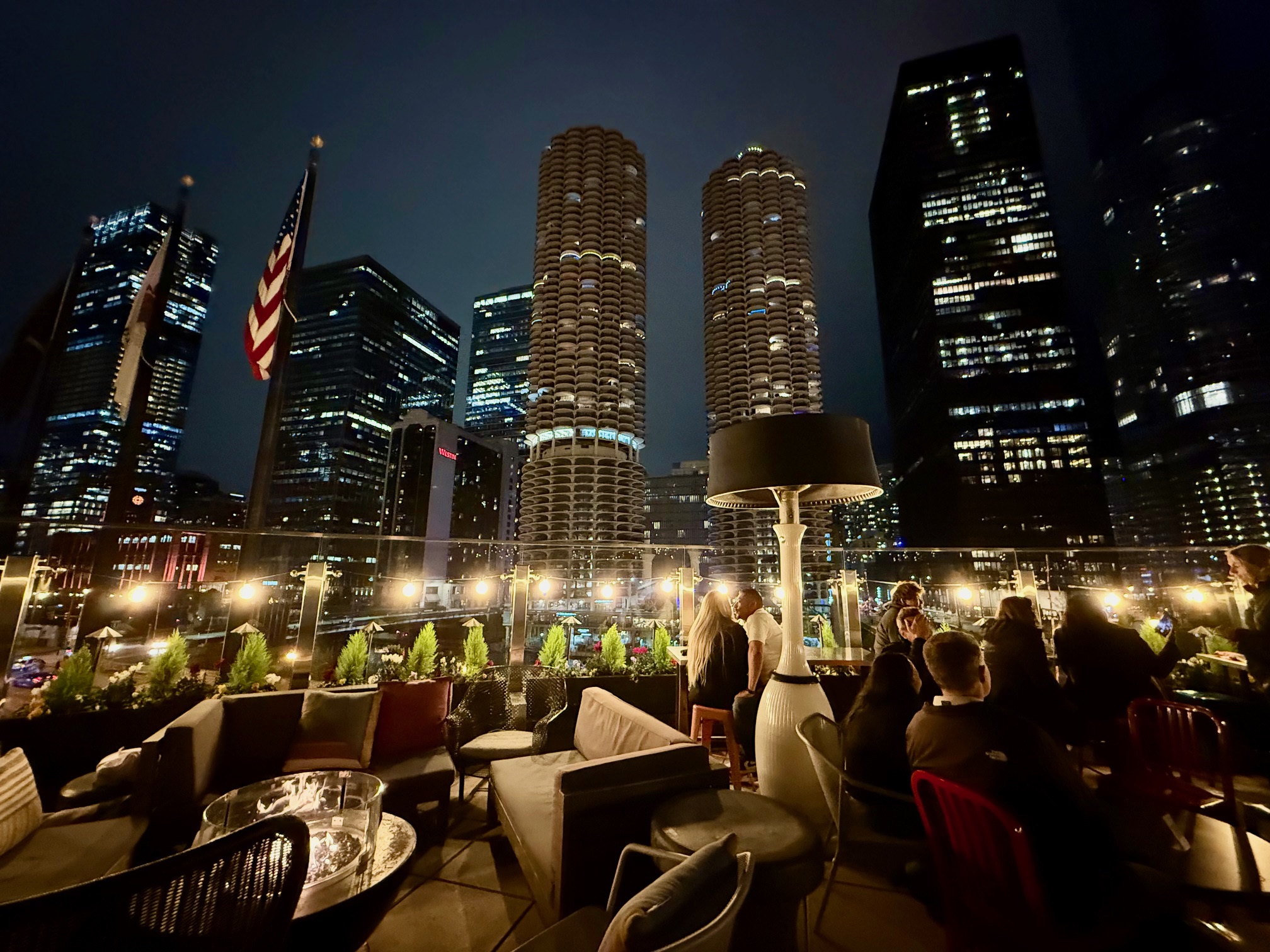 a group of people sitting on a rooftop patio with tall buildings in the background at the Renaissance Chicago