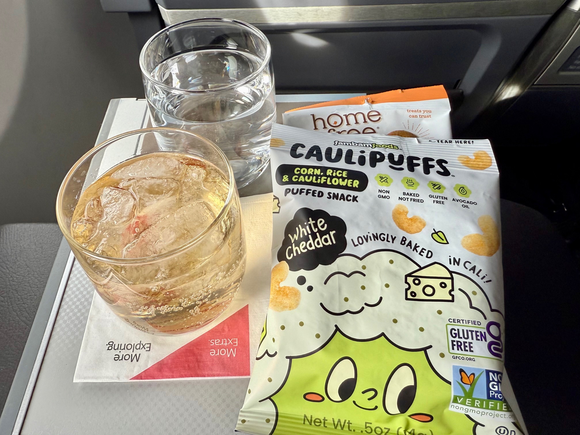a glass of water and a bag of chips on a tray