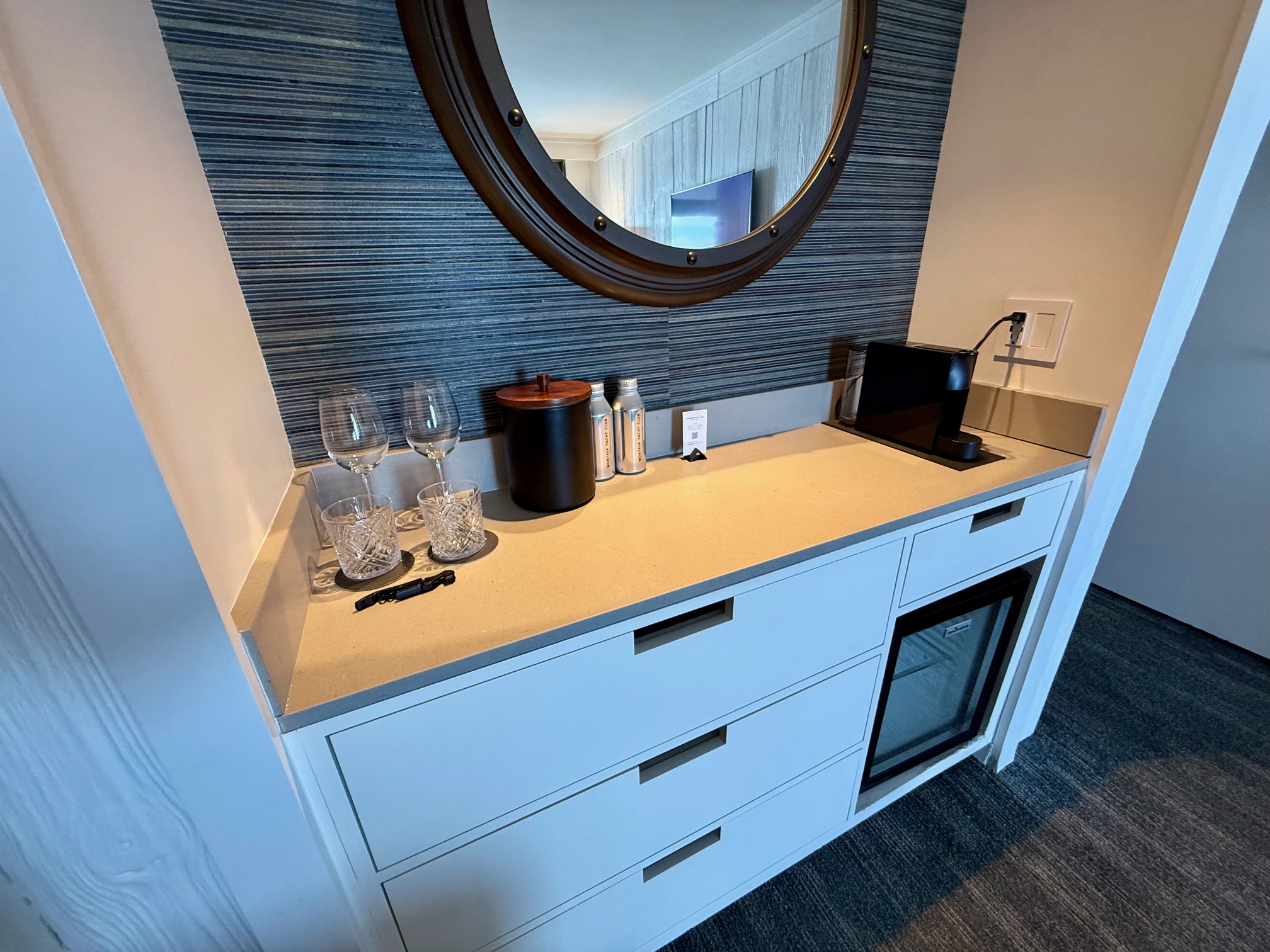 a counter with wine glasses and a mirror