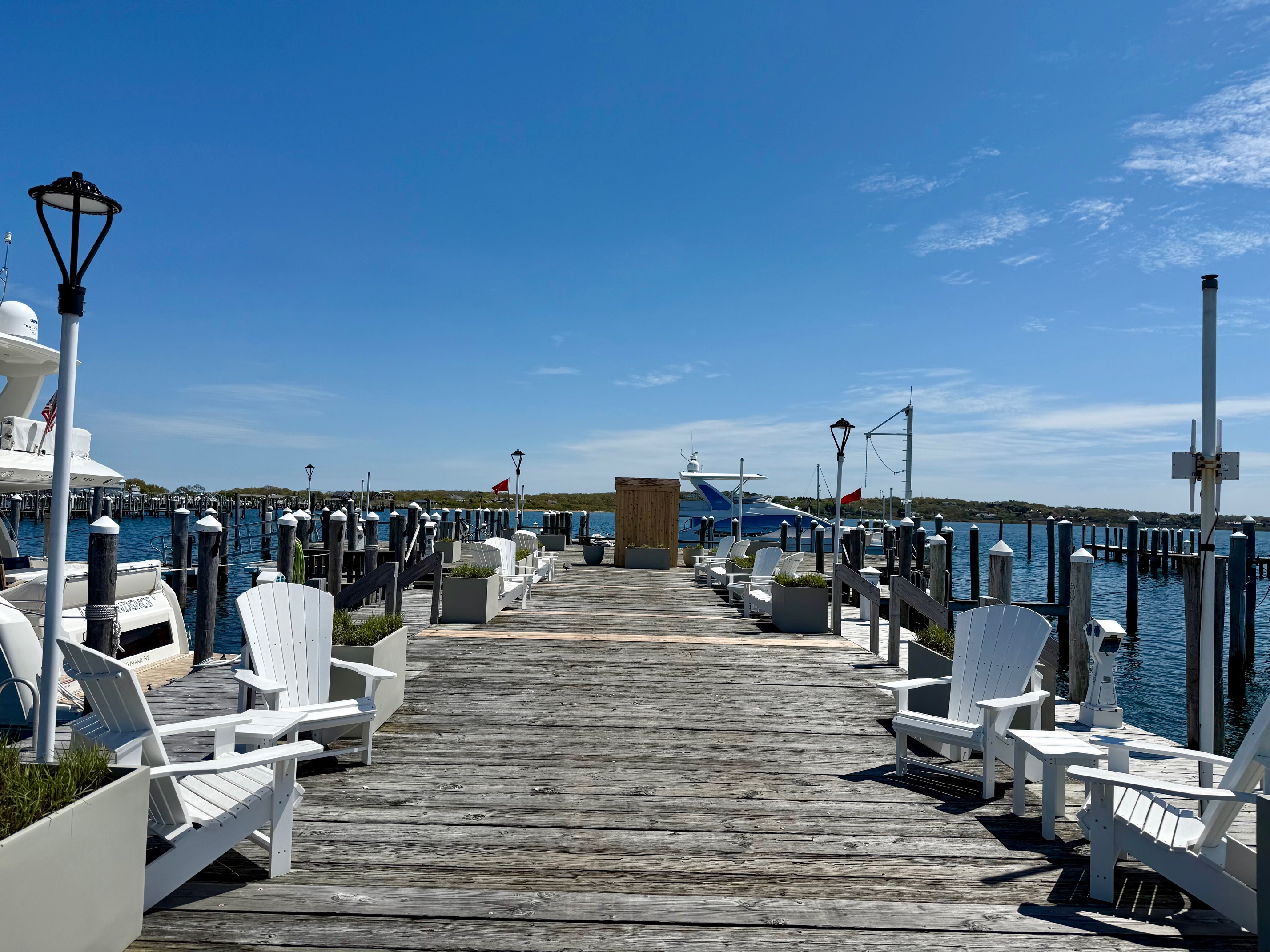 a dock with chairs and boats on the water