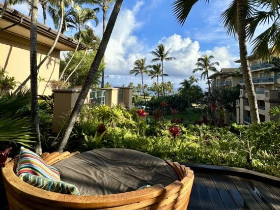 a chair on a deck with palm trees and a blue sky at the Ritz Carlton Maui