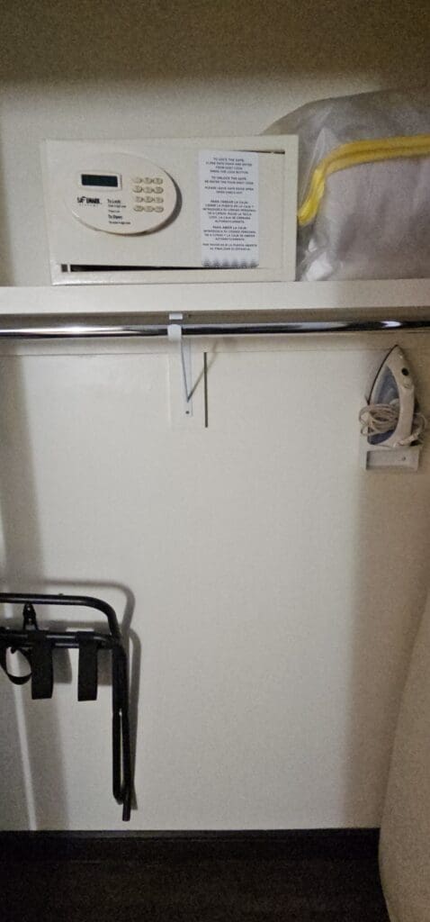 a white closet with a white object on top and a black iron on the wall