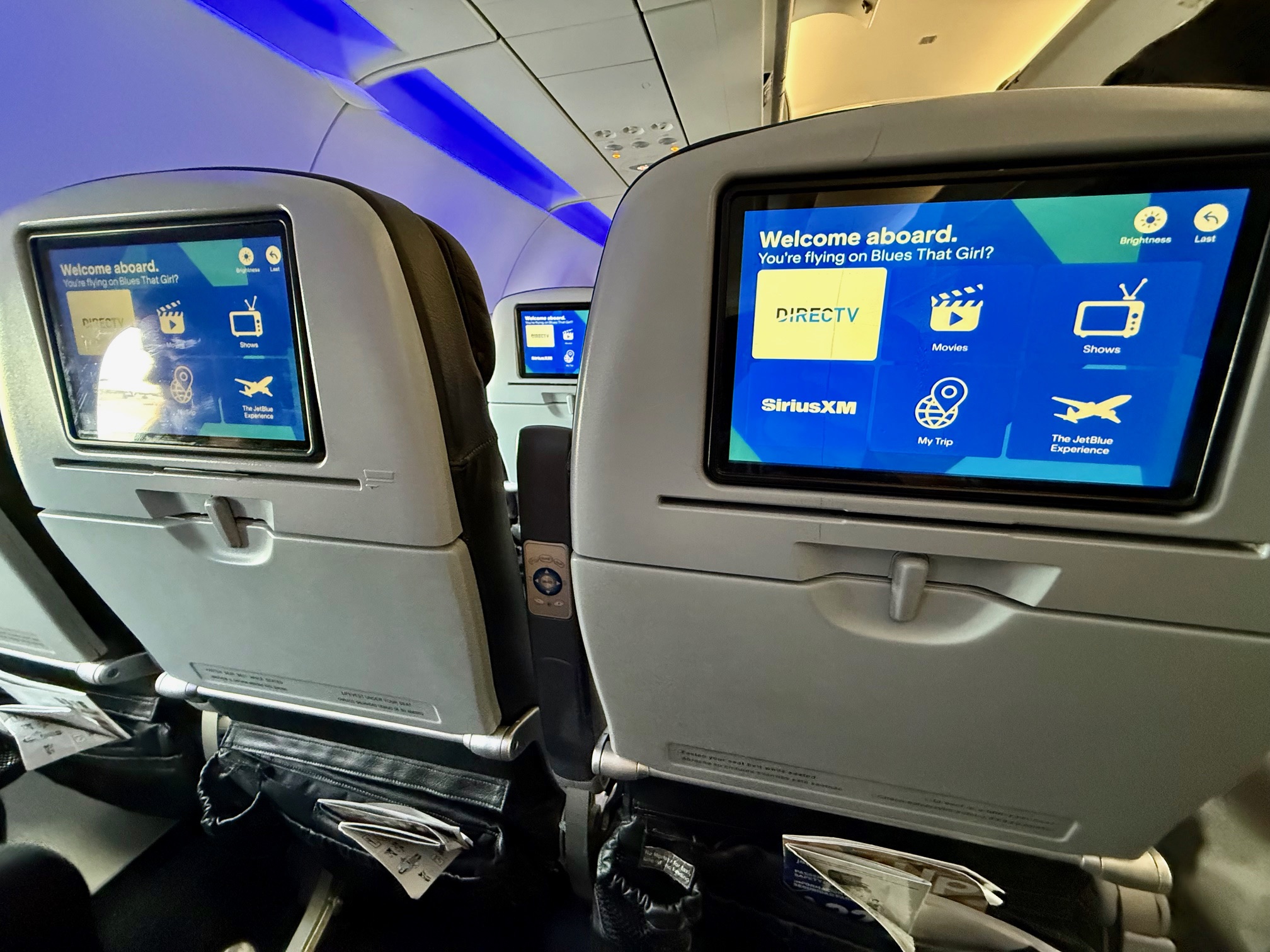 a row of seats with screens on the back of a JetBlue A321 Classic