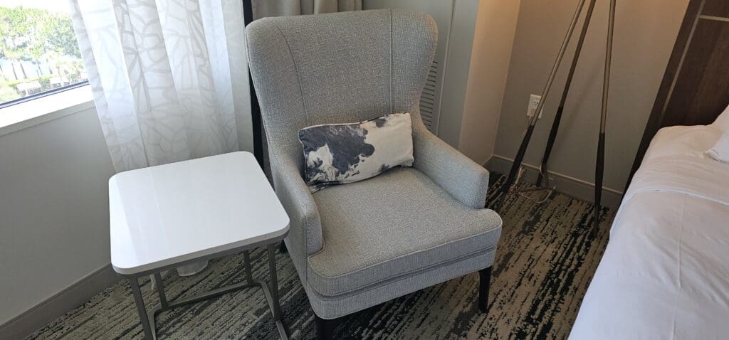 a chair with a pillow next to a table