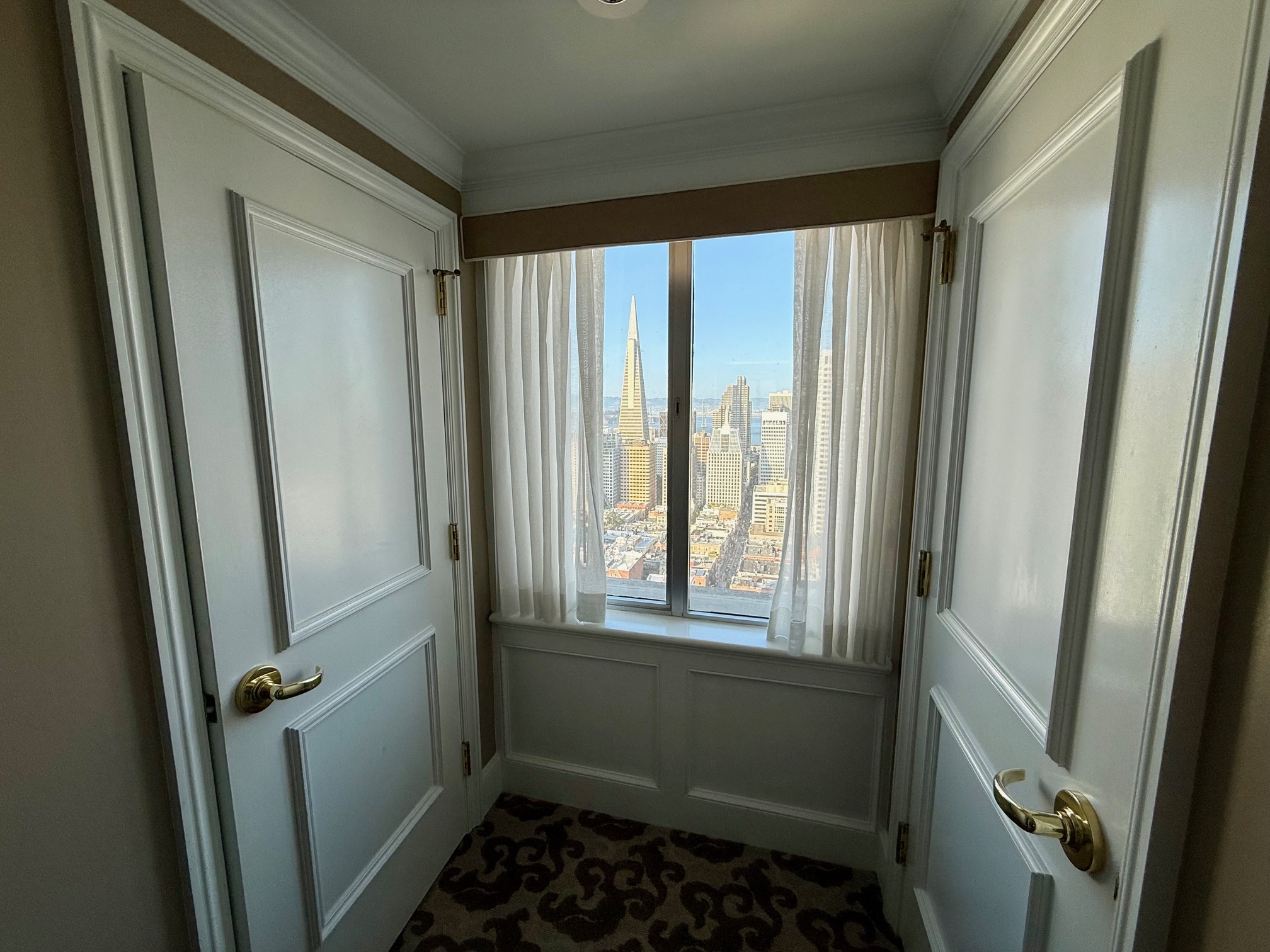a room with white doors and a window with a city view