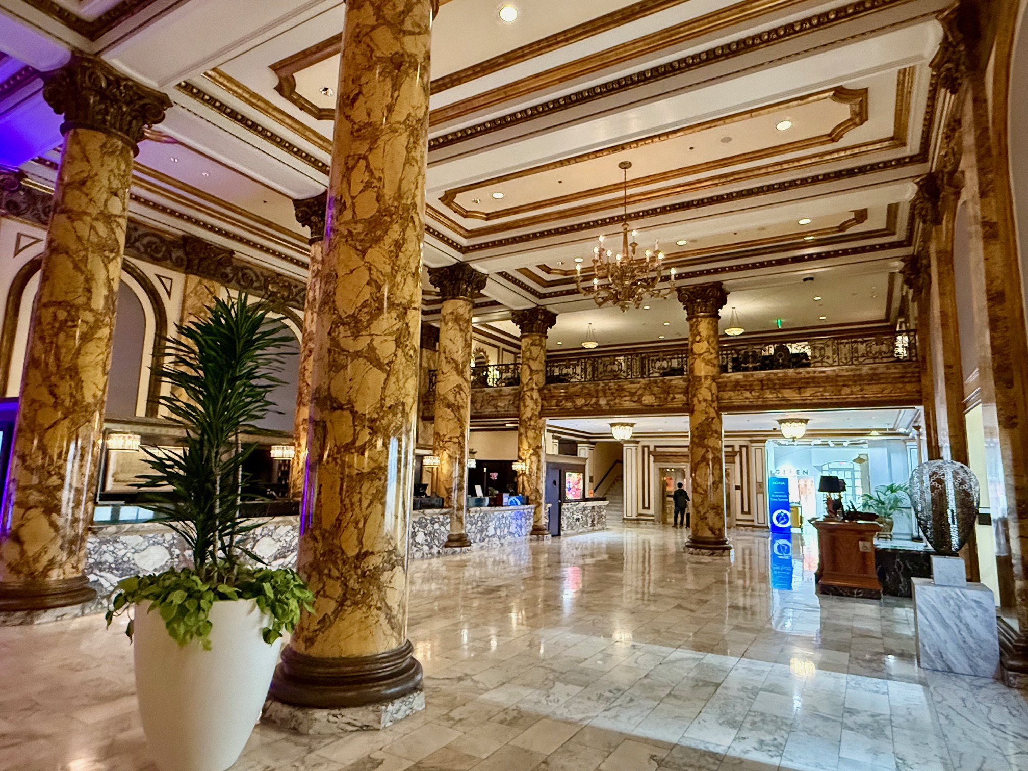 a large marble floor with columns and a chandelier