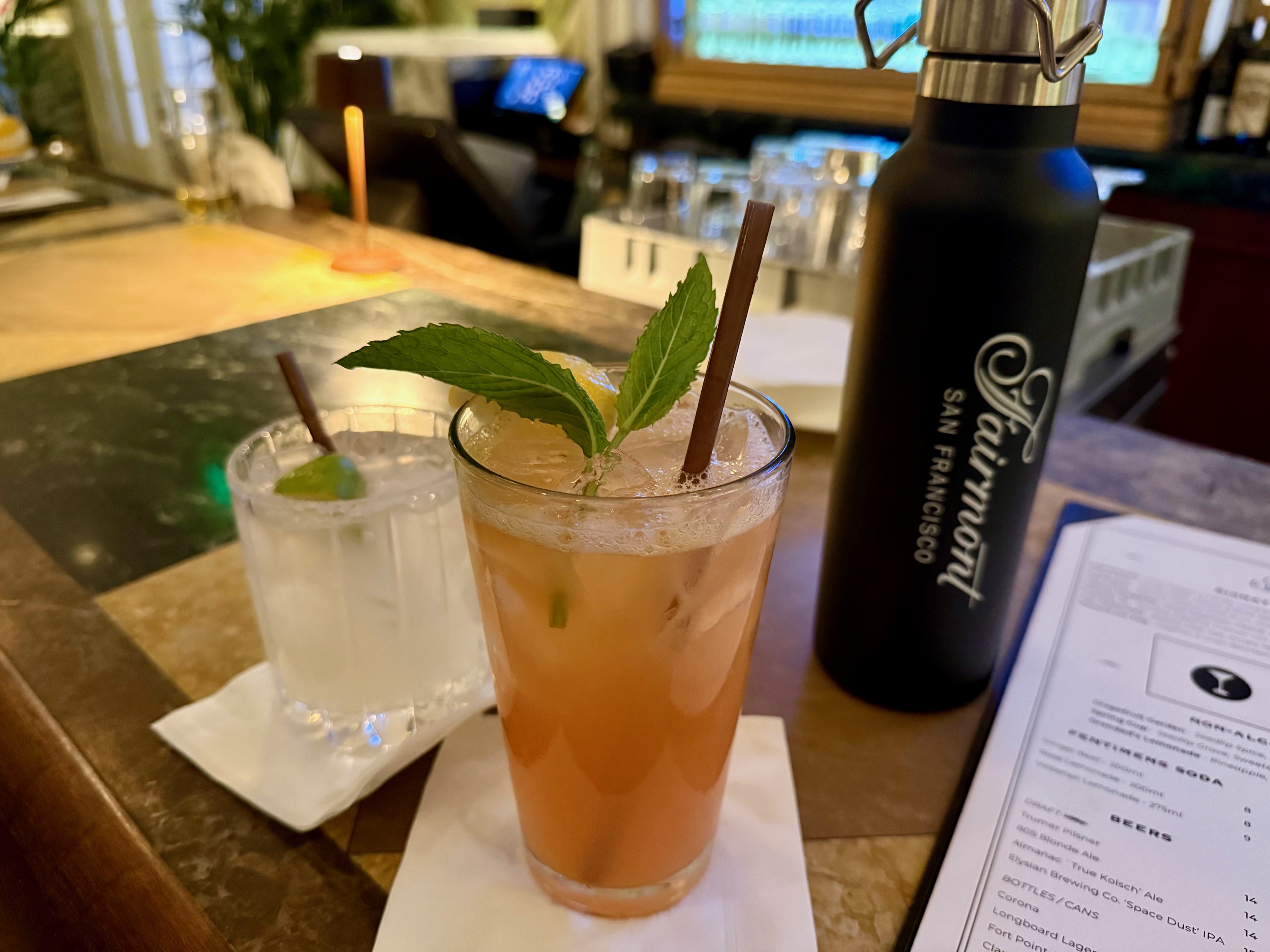 a glass of liquid with a leaf on it next to a bottle
