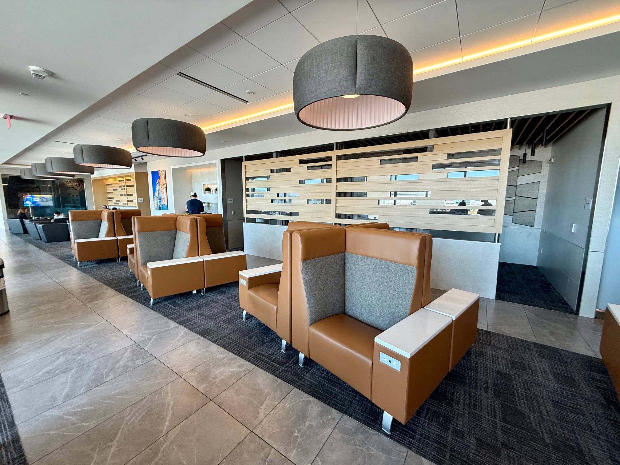 a room with chairs and a man in the background at the American Airlines Admirals Club San Francisco