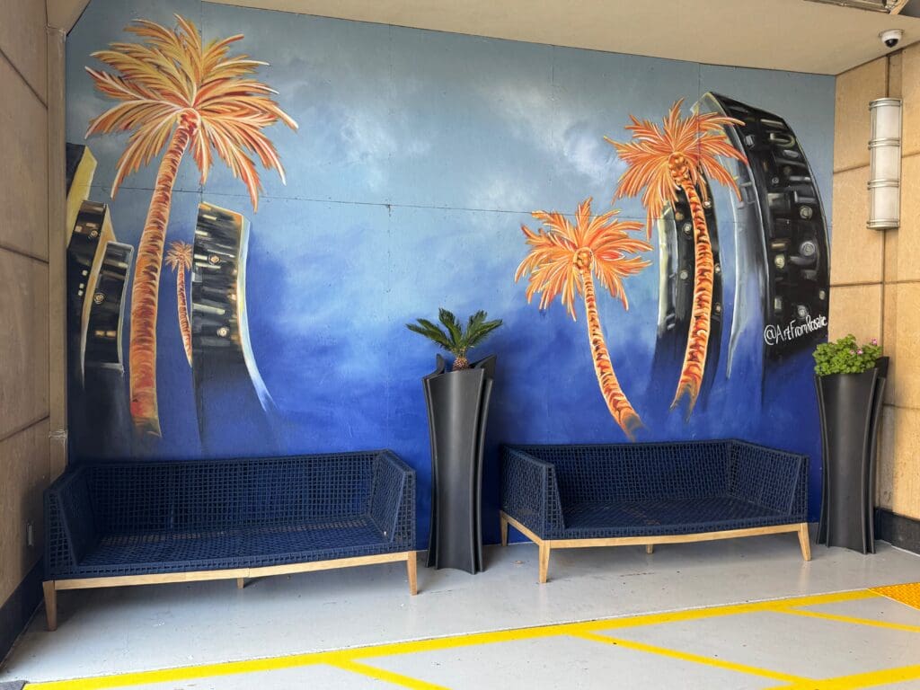 a wall painting of palm trees and a couple of chairs