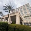 a building with palm trees and a cloudy sky