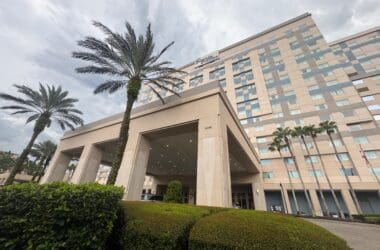 a building with palm trees and a cloudy sky