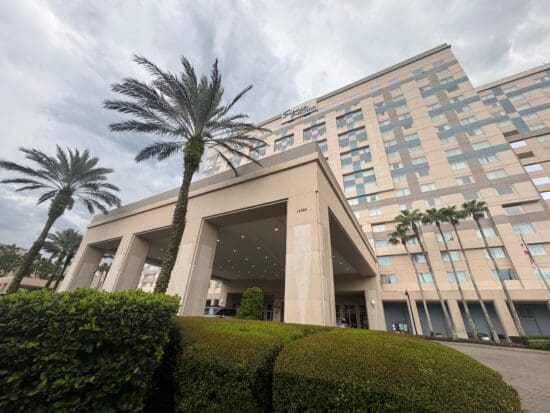 a building with palm trees and a cloudy sky