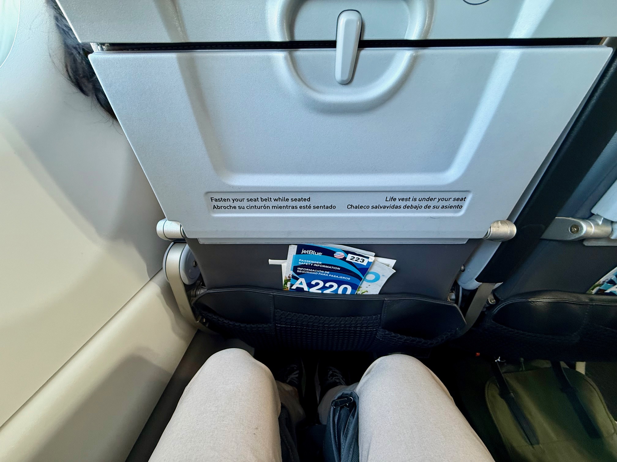 a person's legs in a seat with a pocket in the back