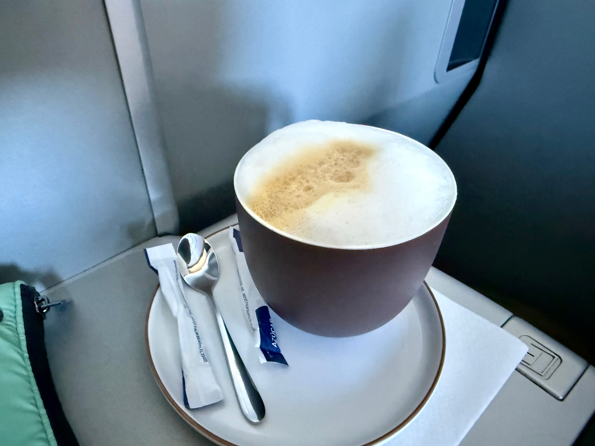 a cup of coffee on a plate with spoon and sugar packets