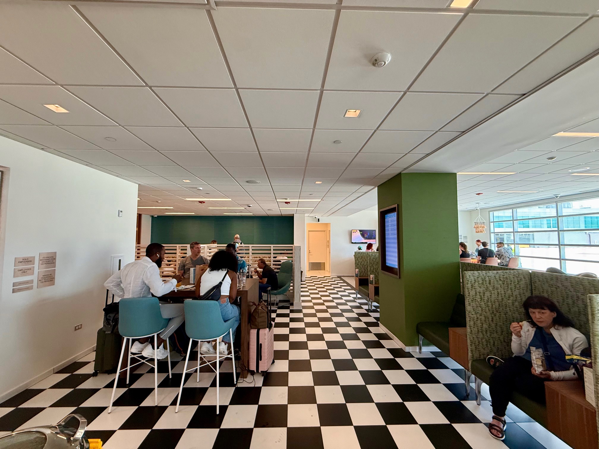 a group of people sitting at tables in a room with black and white checkered floor