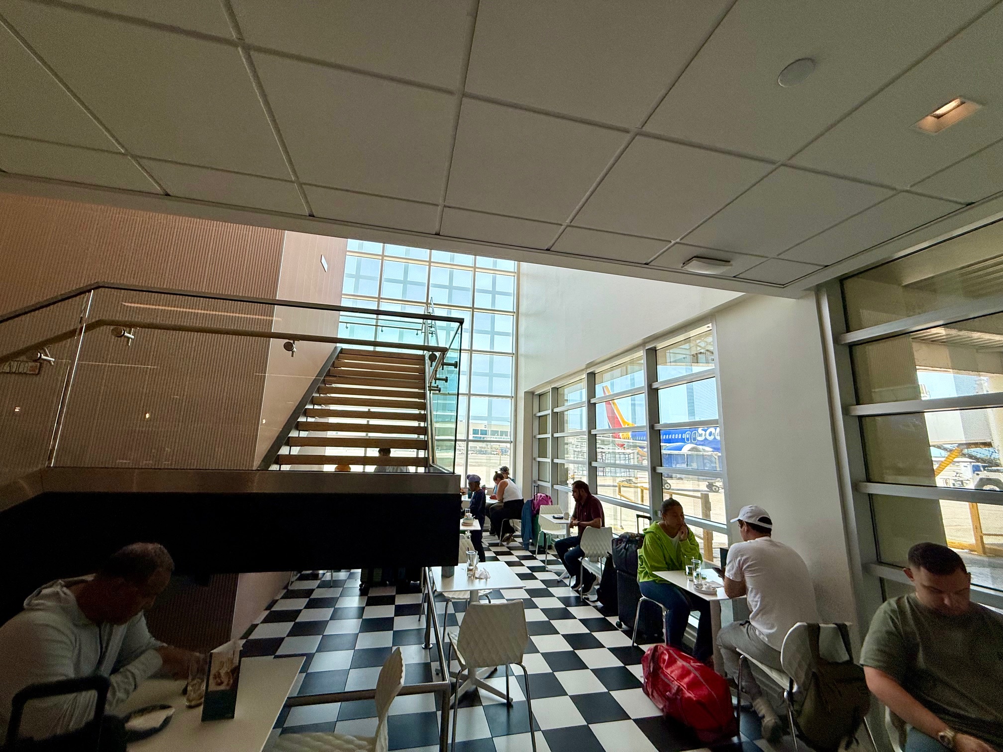 people sitting in a room with a checkered floor and a staircase at the Escape Lounge San Juan