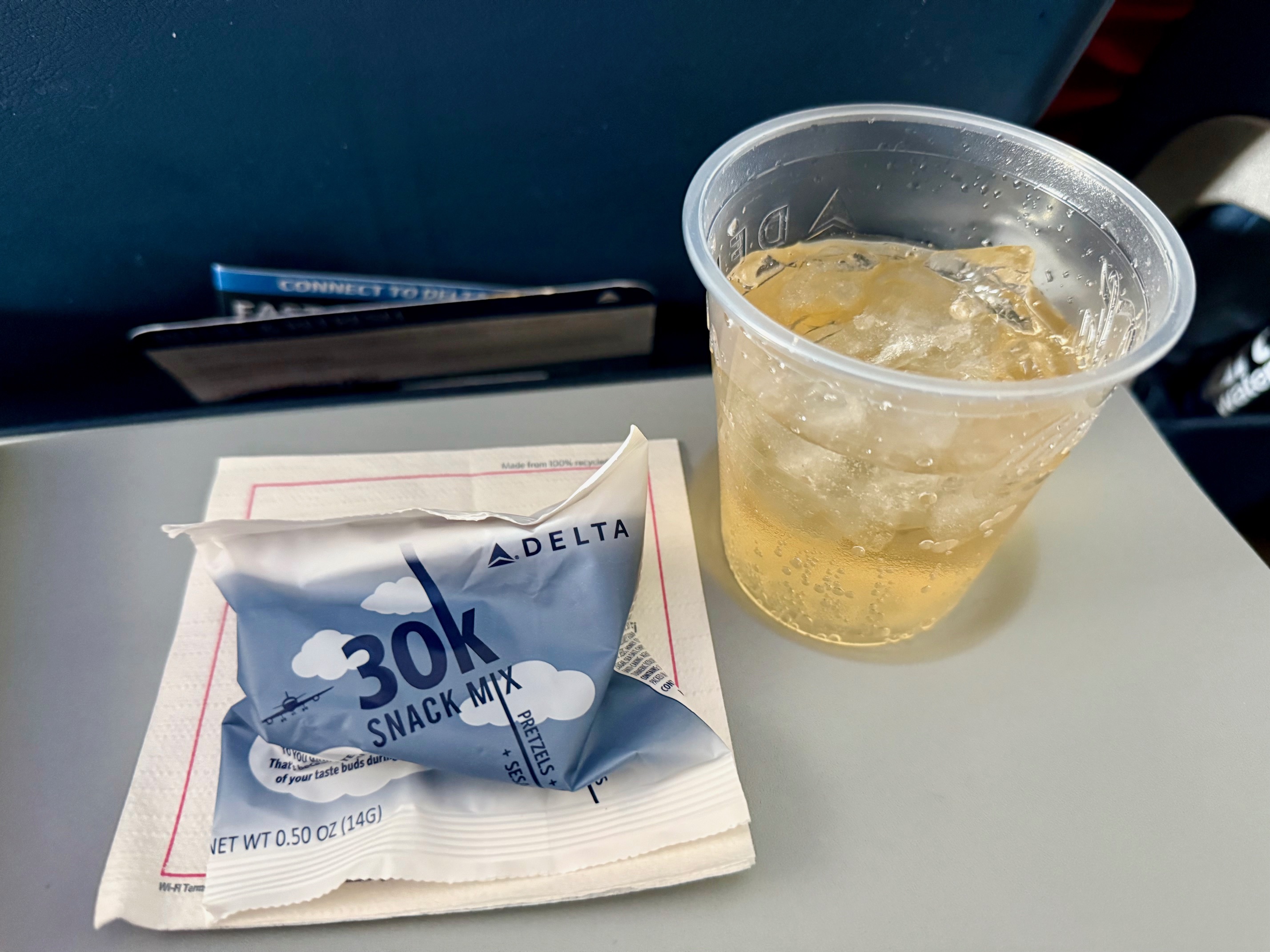 a plastic cup with a drink and a packet of snack mix