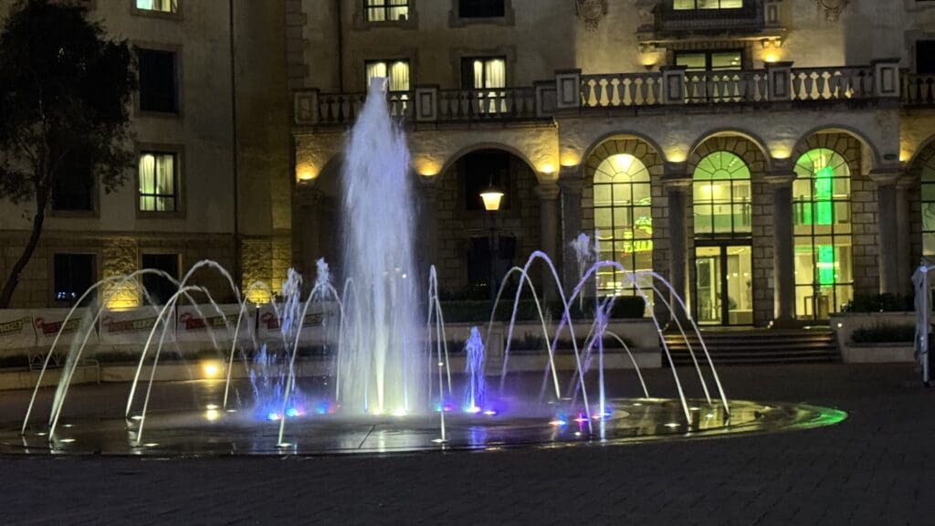 a water fountain with lights in front of a building