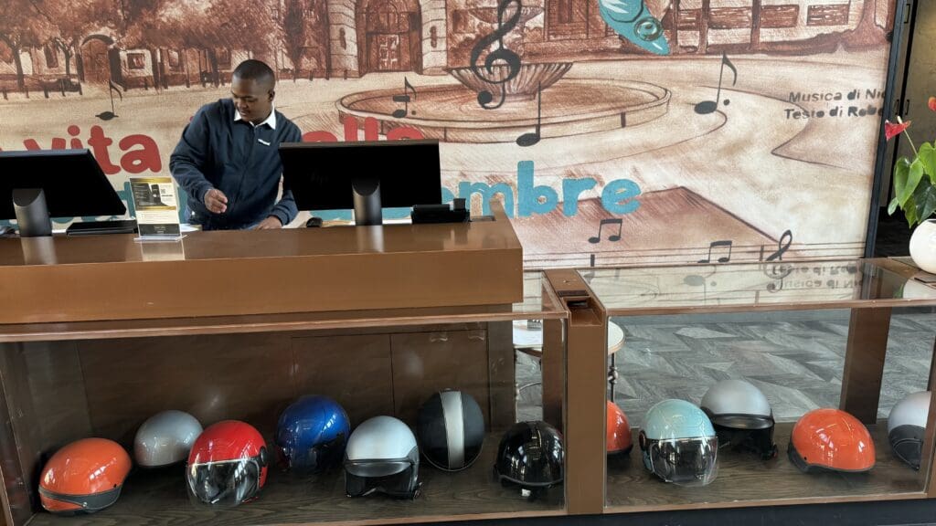 a man standing behind a desk with helmets on it