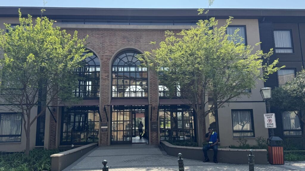 a building with trees and a man sitting on a bench