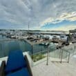 a deck with chairs and a glass railing next to a body of water