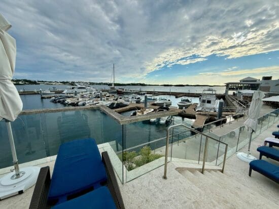 a deck with chairs and a glass railing next to a body of water