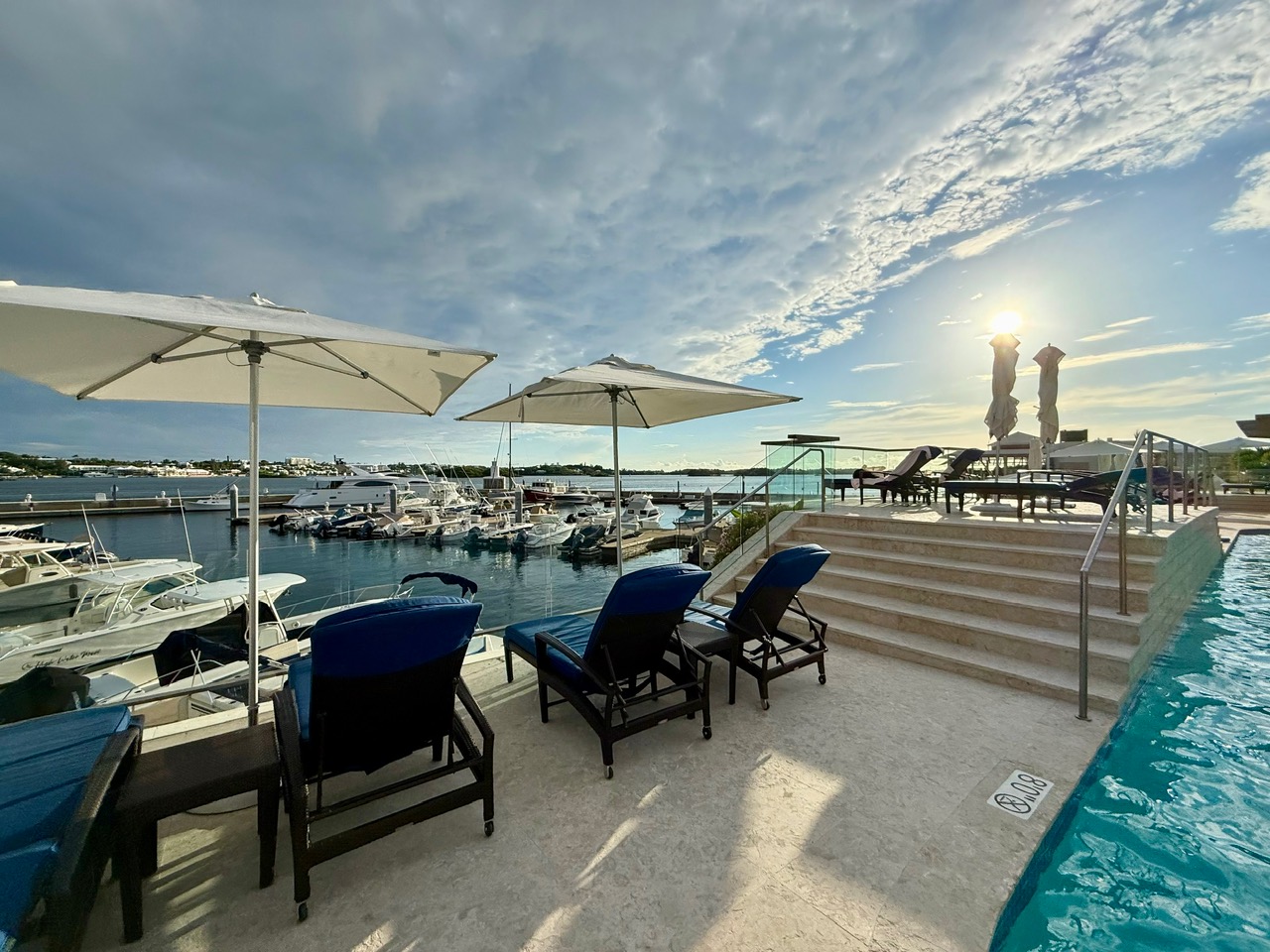 a pool with chairs and umbrellas by the water