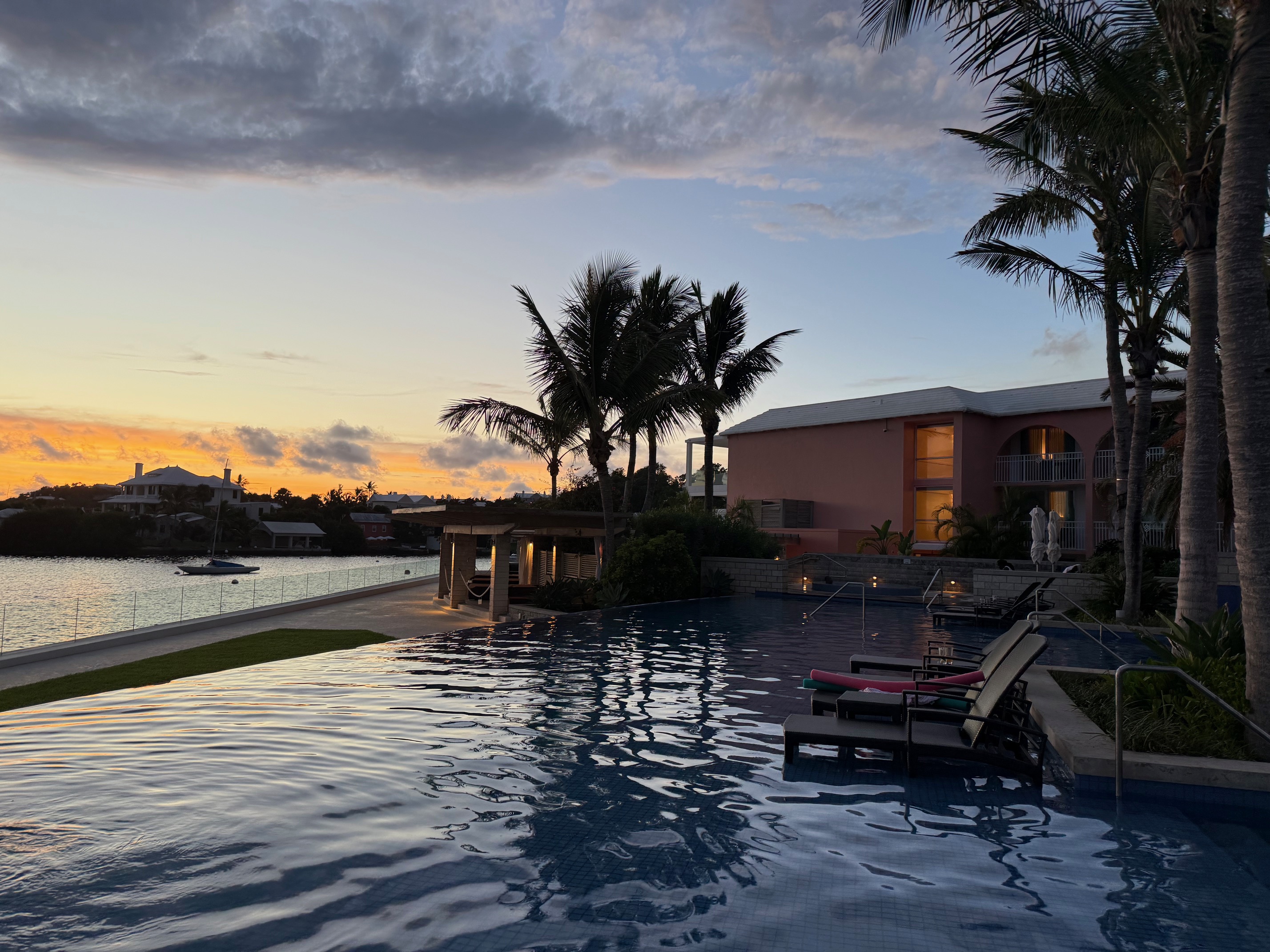 a pool with chairs and palm trees in front of the Fairmont Hamilton Princess