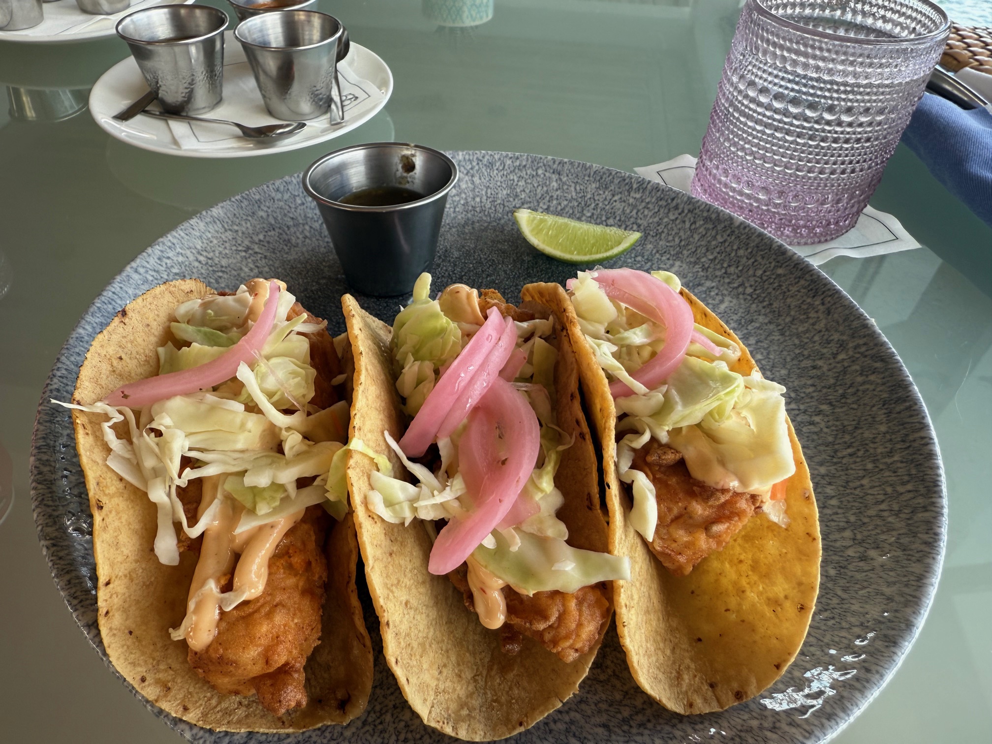 a plate of tacos with sauce and lime