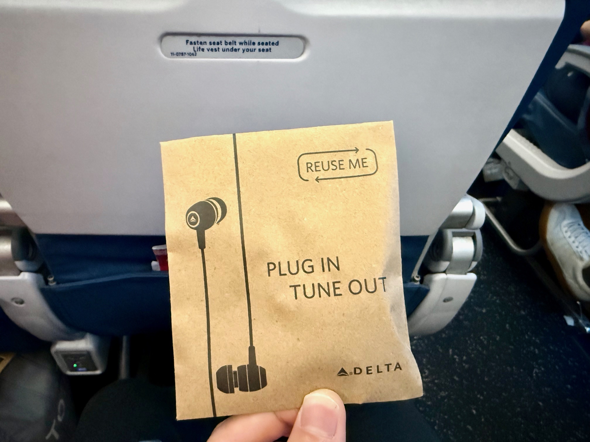 a hand holding a brown paper with earbuds on it