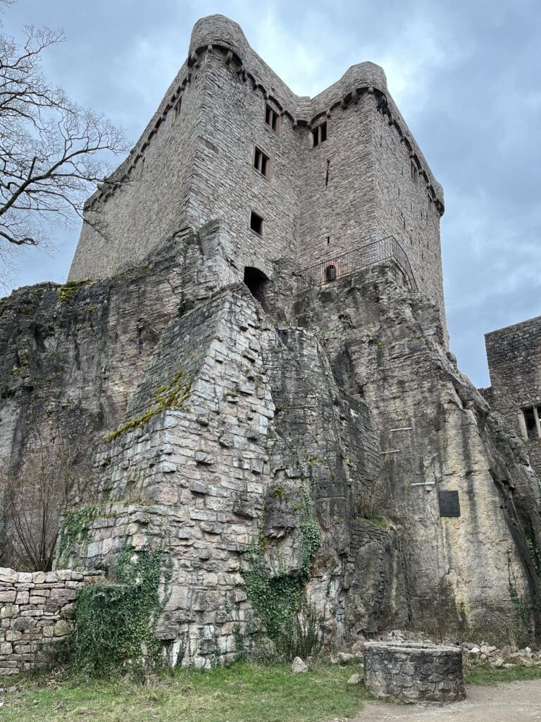 a stone castle with a stone wall with Peveril Castle in the background