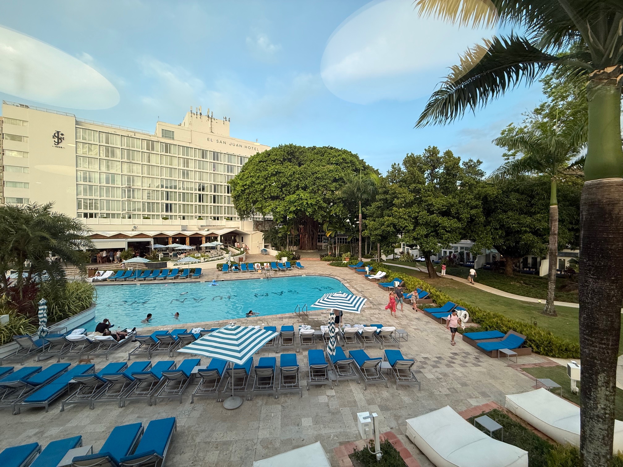 a pool with lounge chairs and trees and buildings