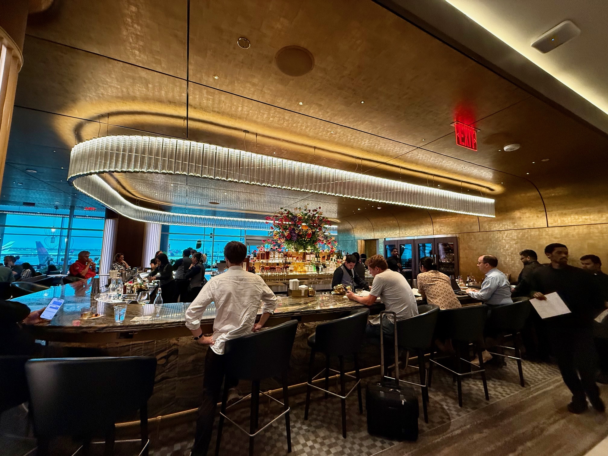 a group of people sitting at a bar at the Delta One Lounge New York JFK