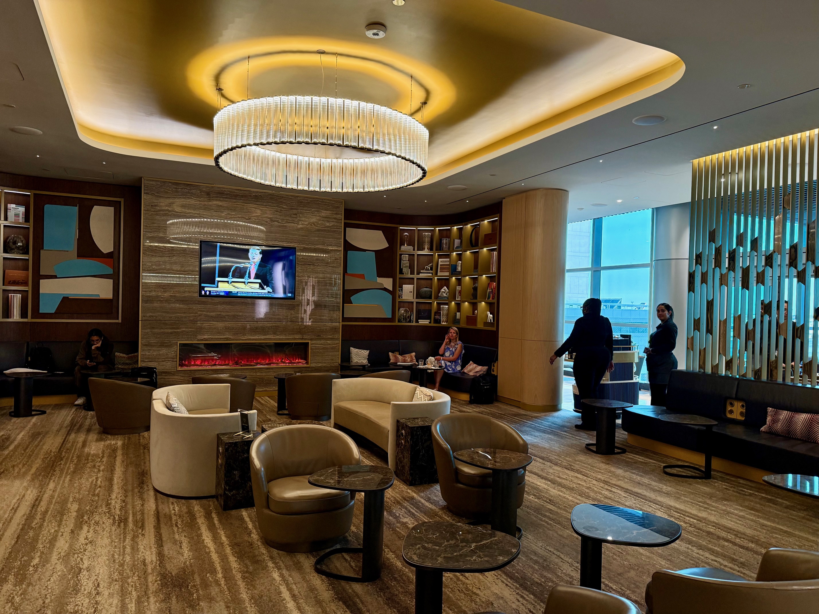 a room with a large chandelier and a television at the Delta One Lounge New York JFK