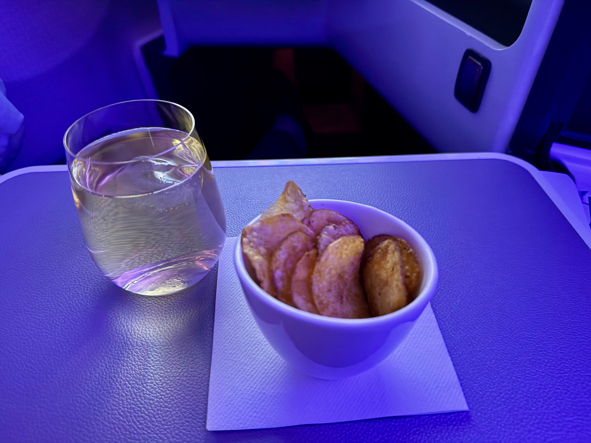 a bowl of chips and a glass of water on a table in Virgin Atlantic A350 Upper Class
