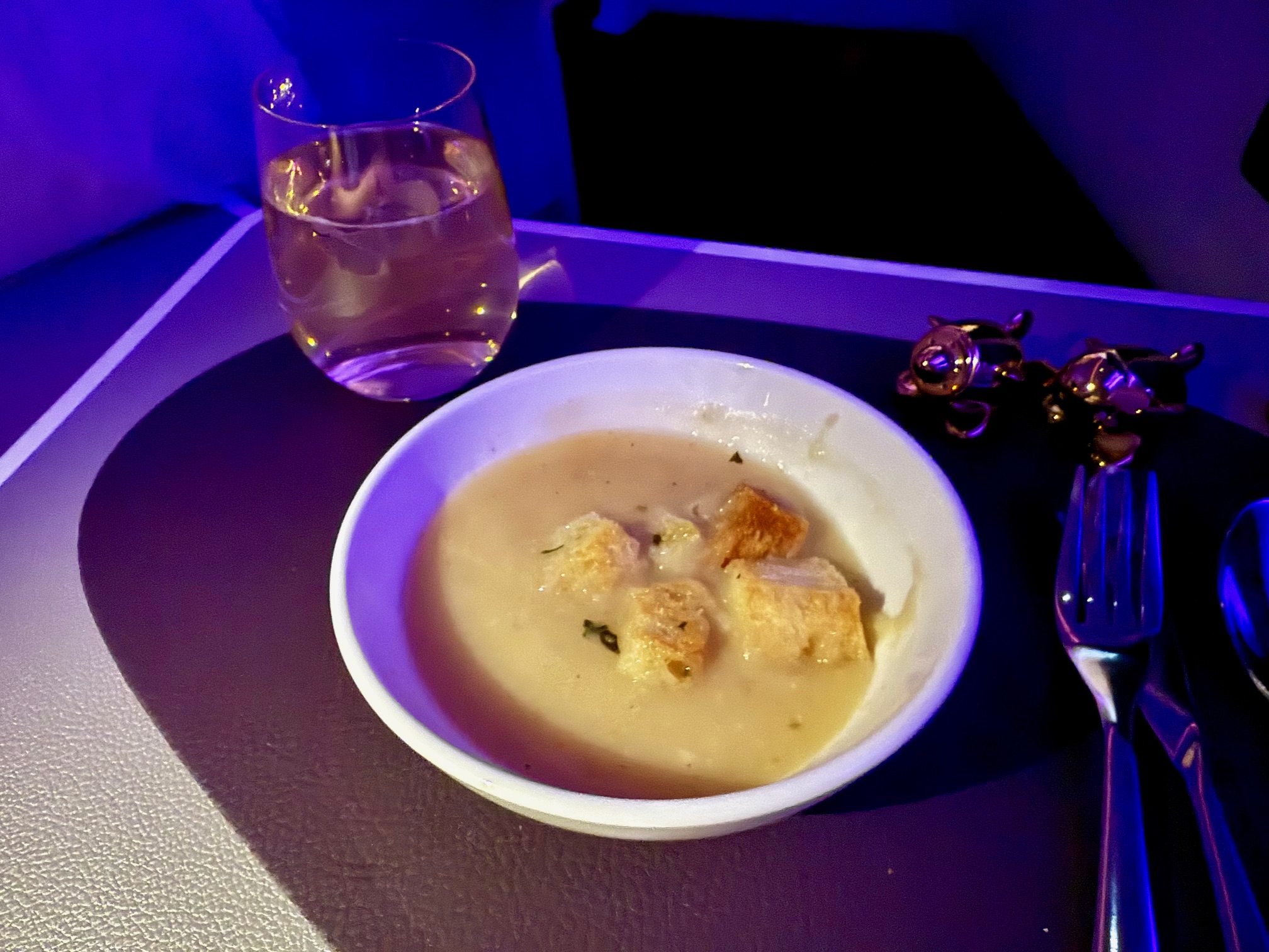 a bowl of soup and a glass of water on a tray