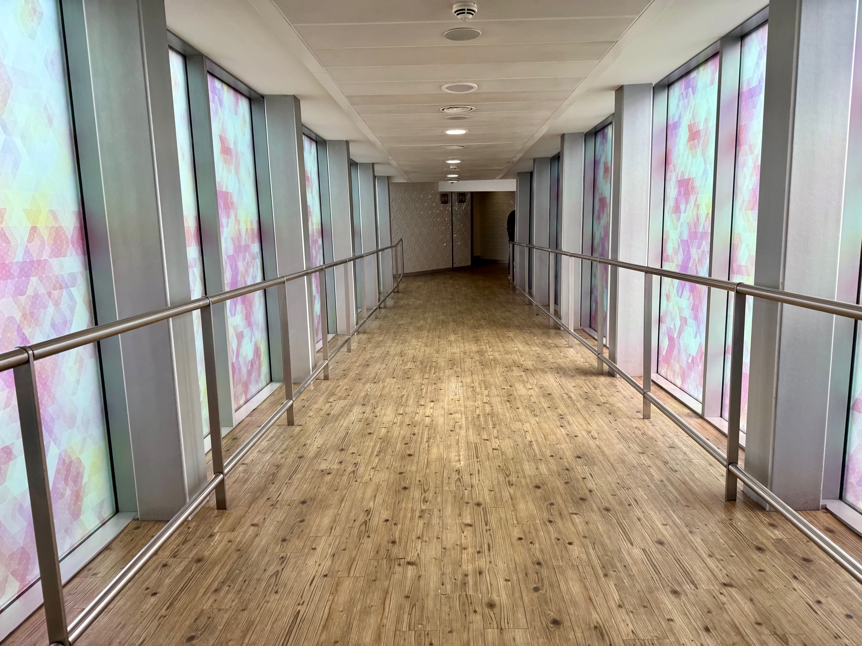a long hallway with a wood floor and metal railings