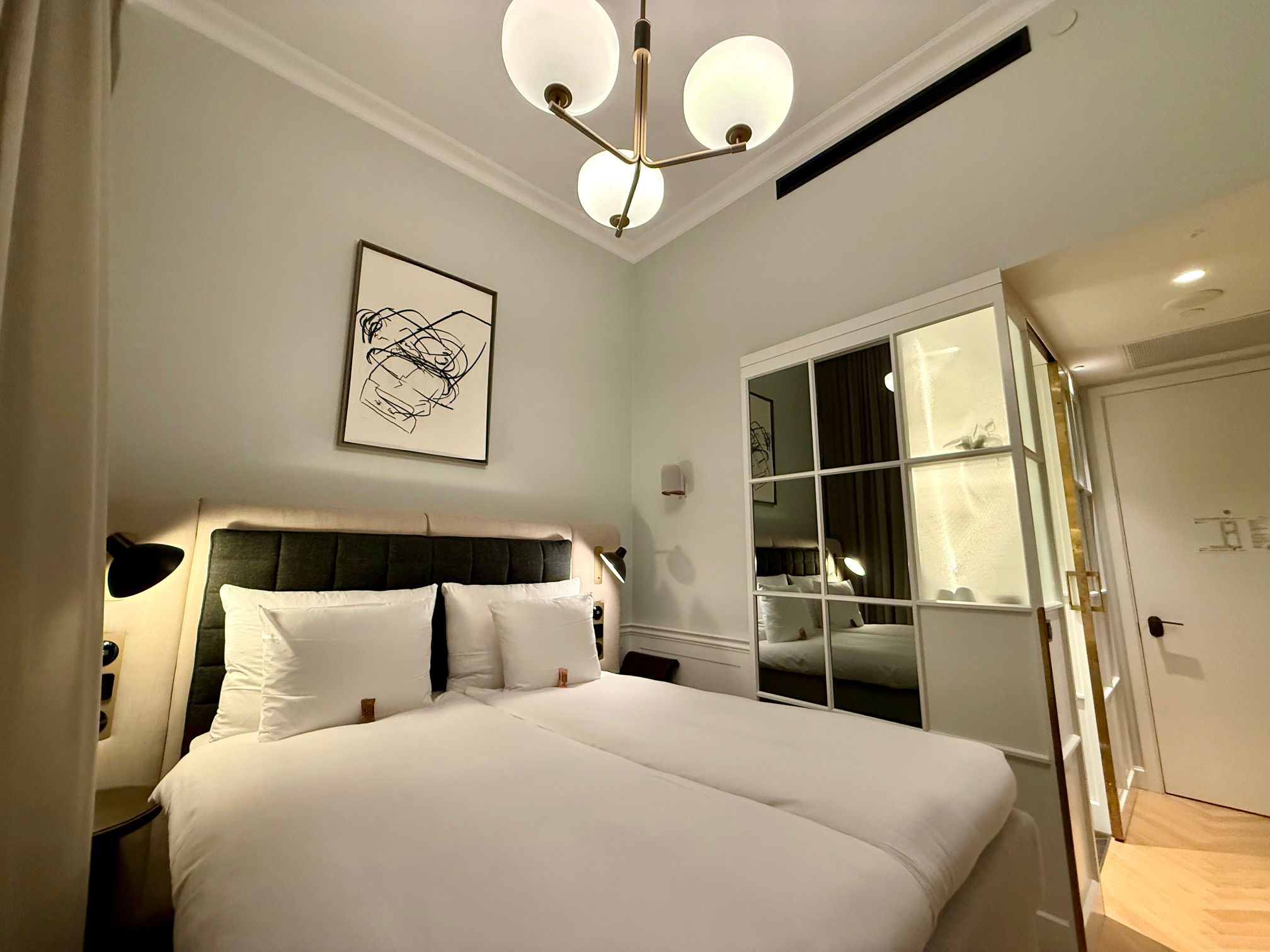 a bed with white sheets and a chandelier