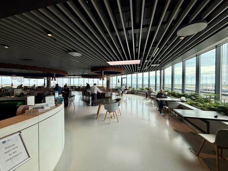 The Eventyr Lounge with tables and chairs and a large window at Copenhagen Airport