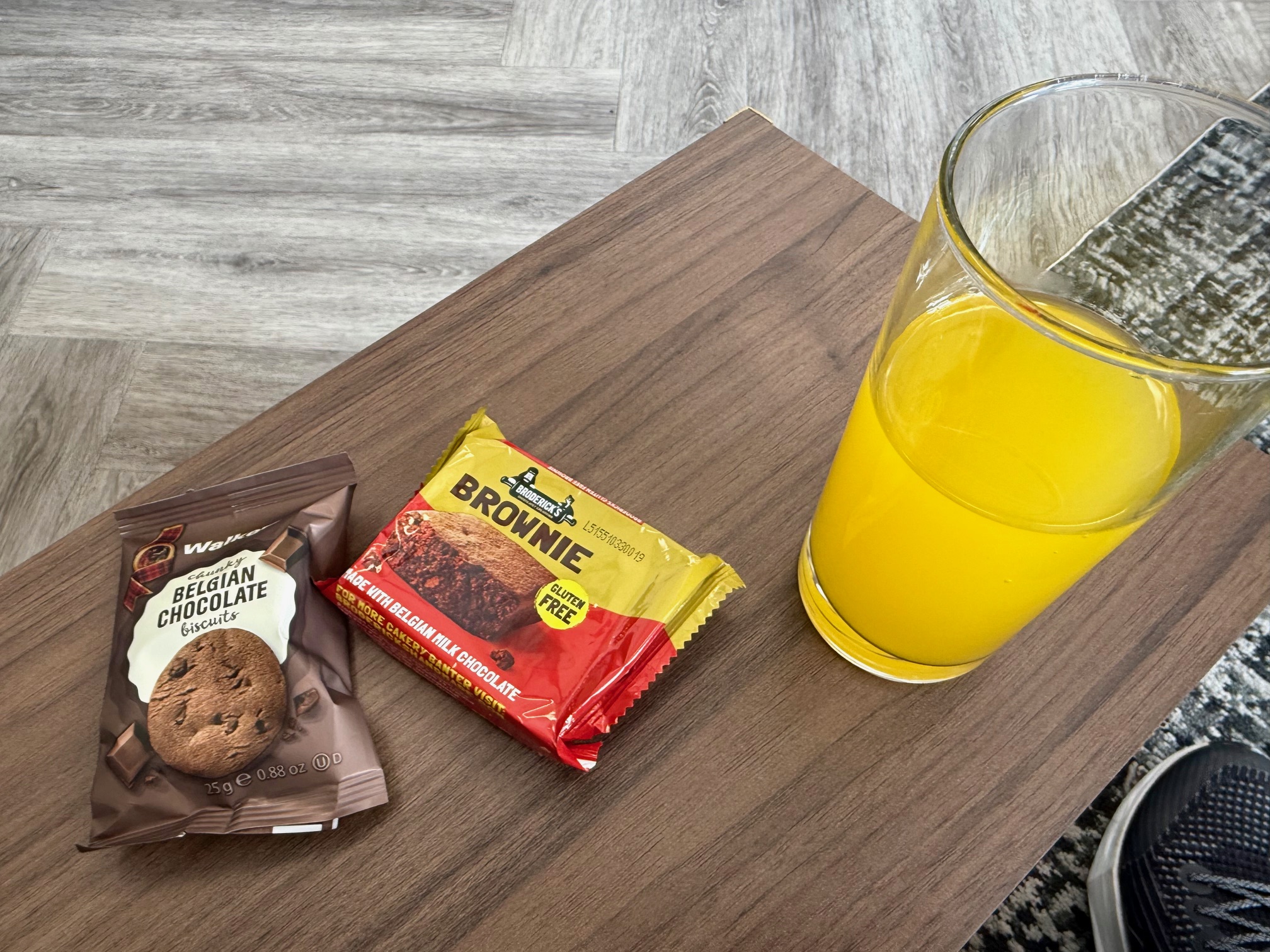 a glass of orange juice next to a chocolate bar and cookies