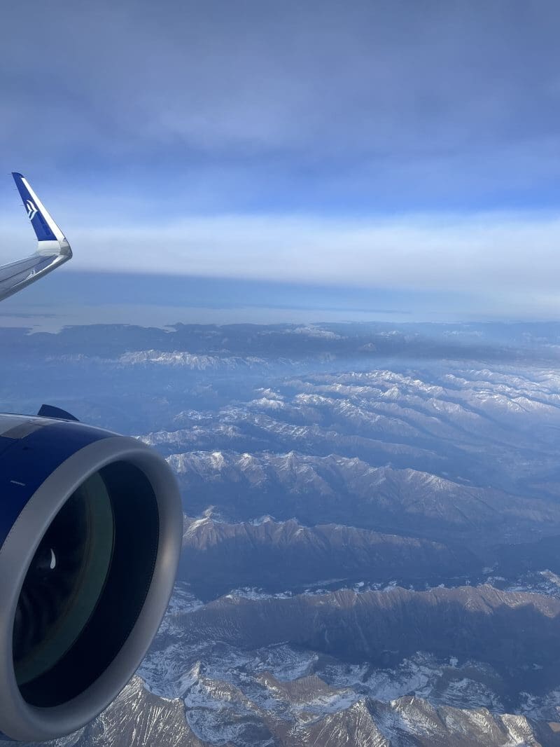 an airplane wing and engine above mountains