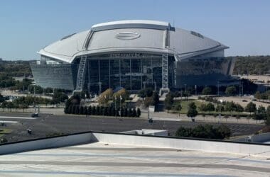 a large stadium with a large roof with AT&T Stadium in the background