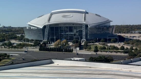 a large stadium with a large roof with AT&T Stadium in the background