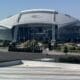 a large stadium with a large roof with AT&T Stadium in the background
