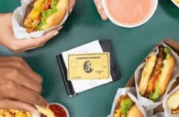 An image showing an American Express Gold Card on a table next two burgers and fries