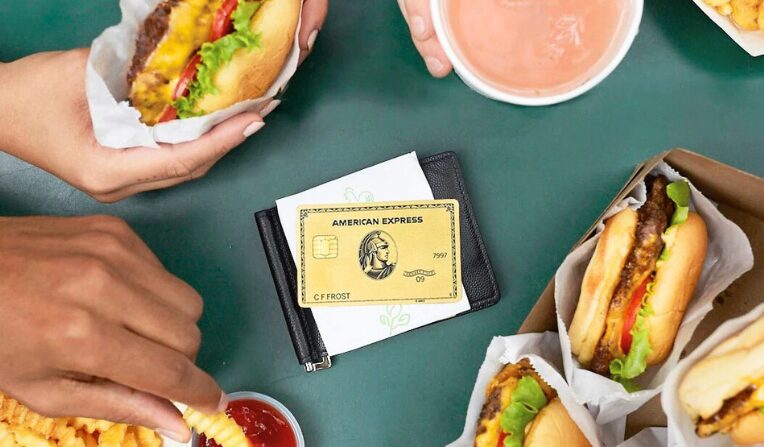 An image showing an American Express Gold Card on a table next two burgers and fries