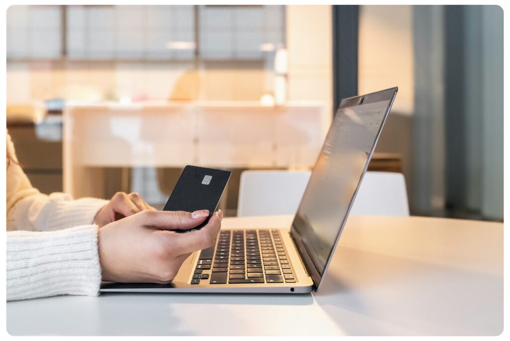 A woman holding a credit card and using a laptop