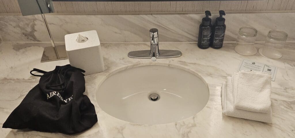a sink with a silver faucet and a black bag on the counter