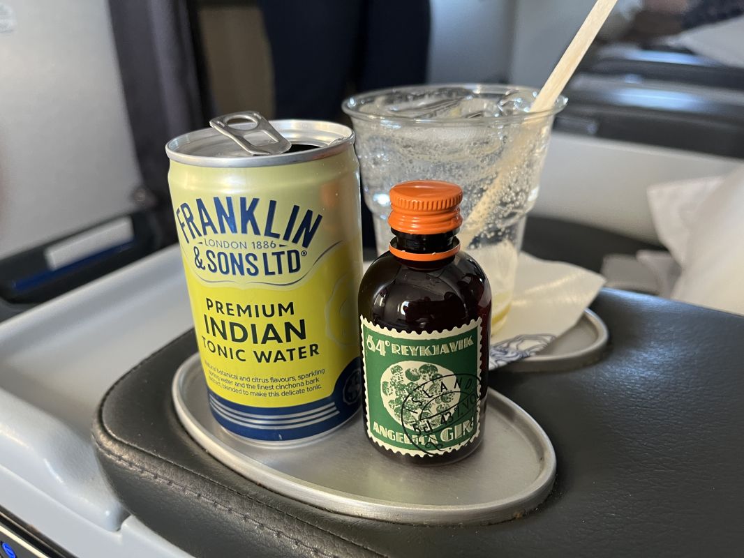 a can of soda and a glass of water on a tray